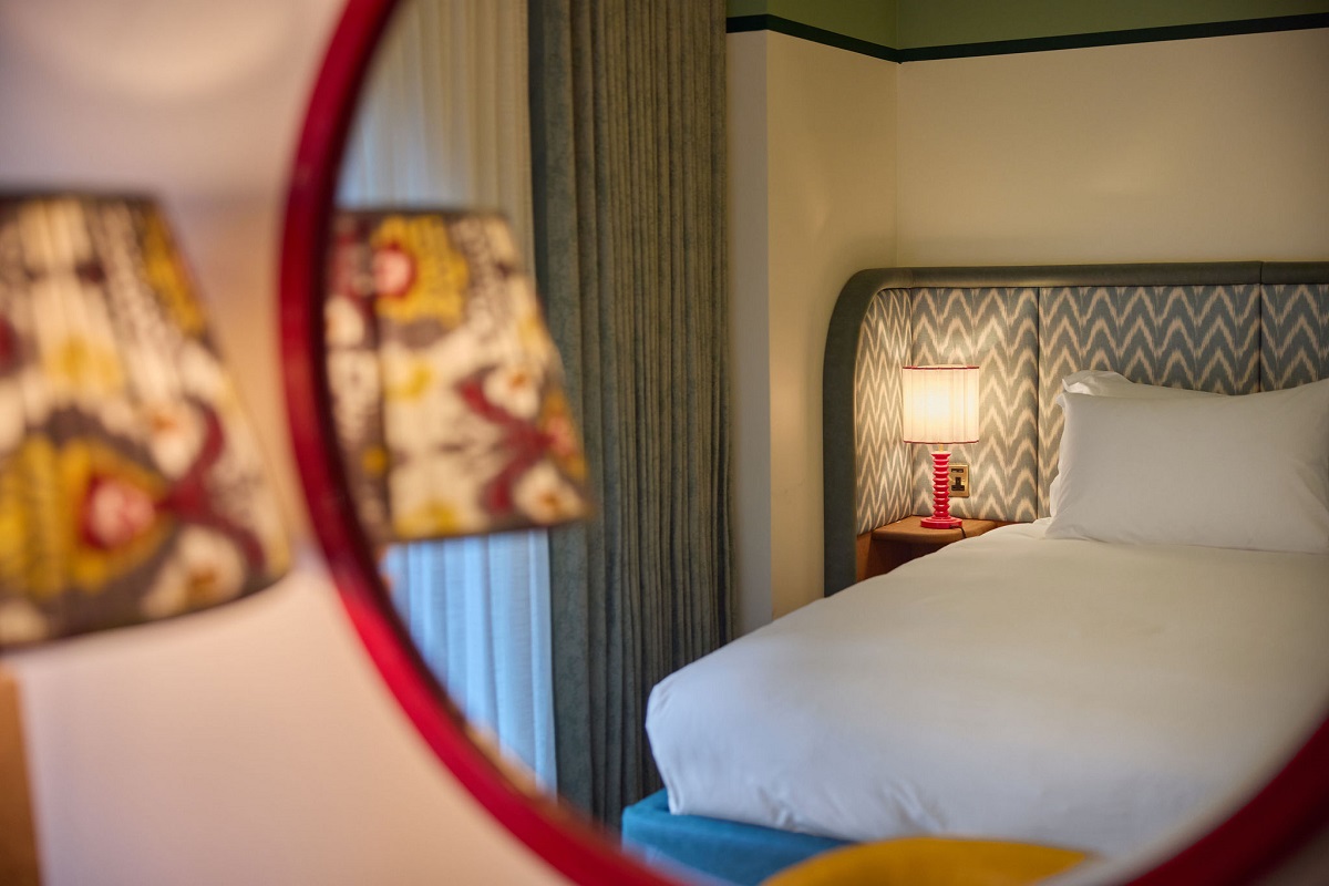 view of bed in hotel guestroom through round mirror