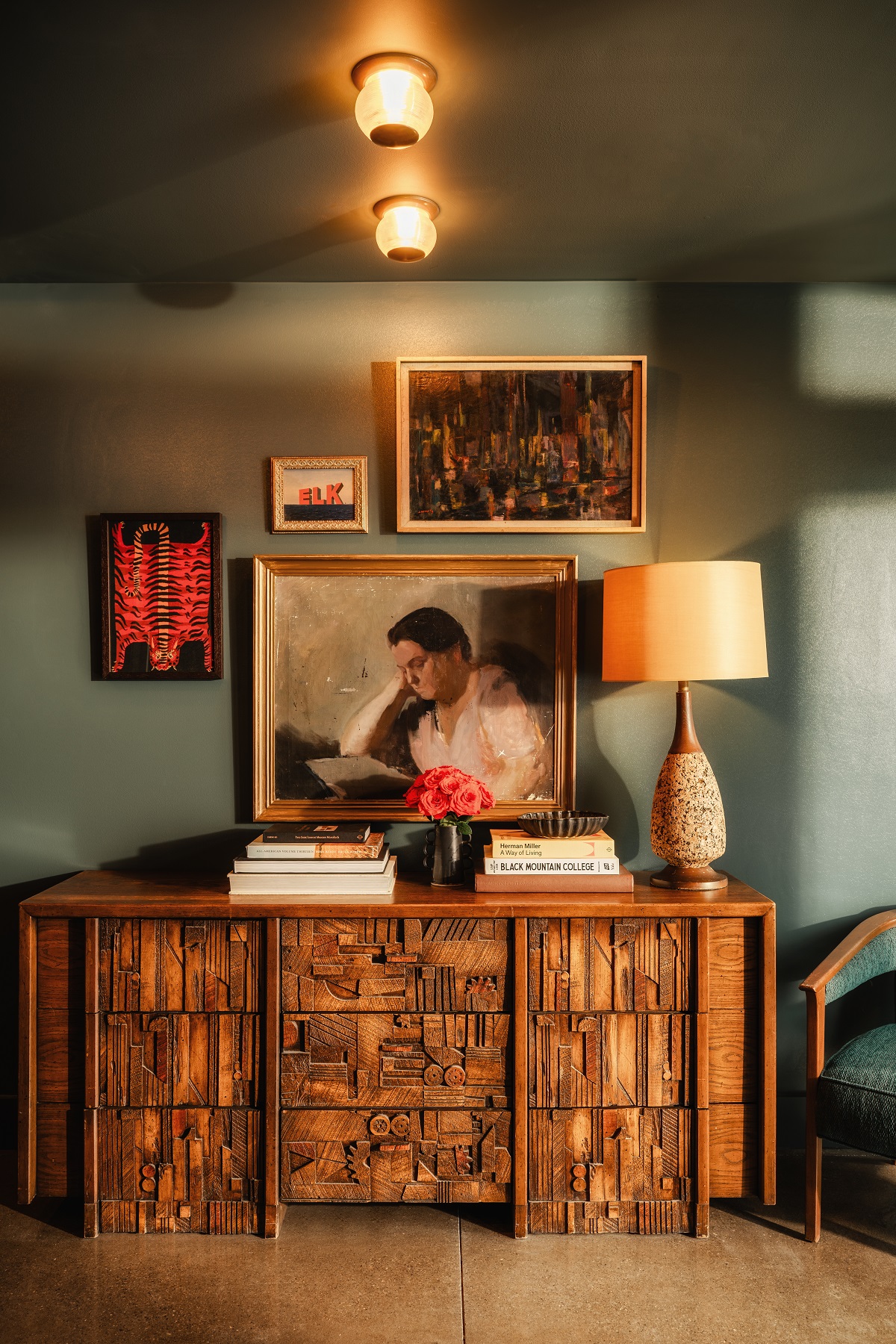 a gallery of vintage art above mid century wooden cabinet