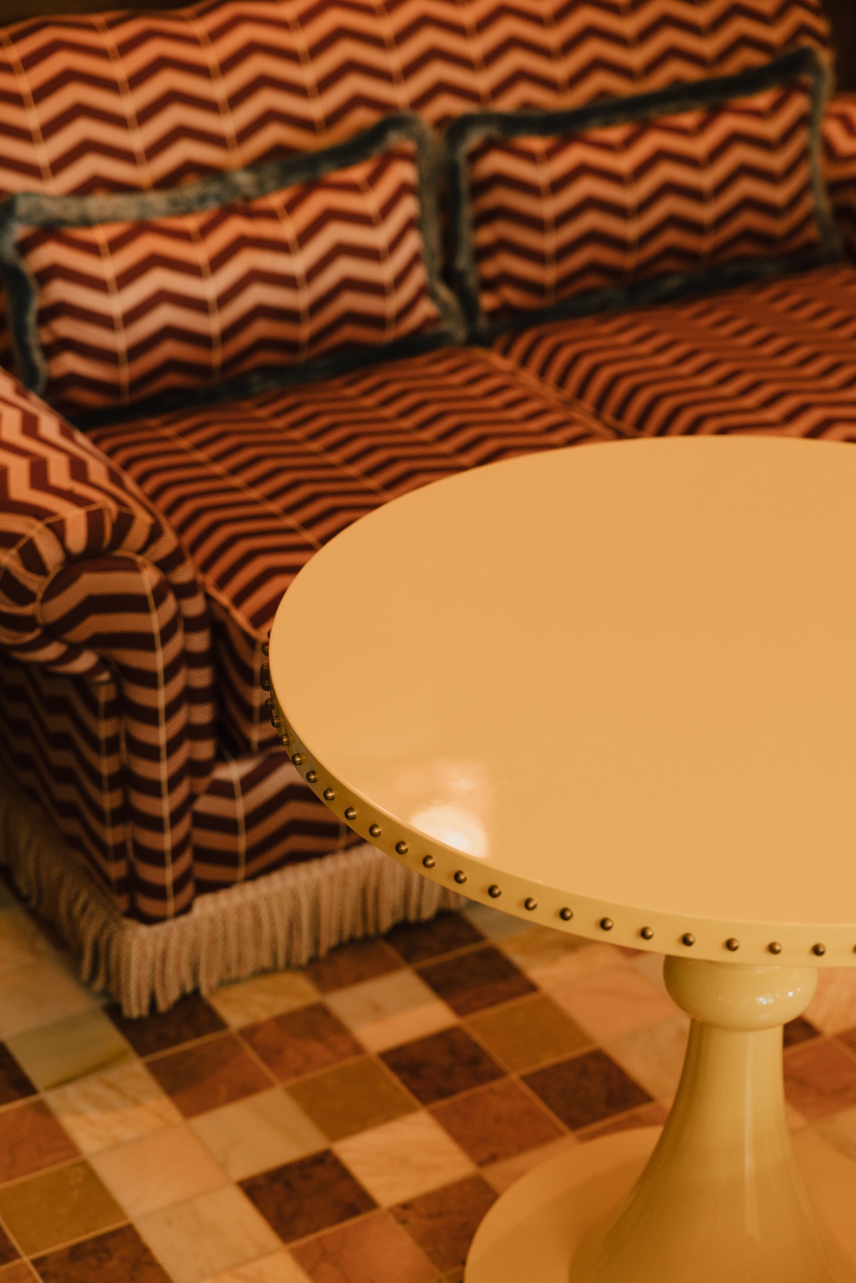 round table with stud detail next to upholstery and floor pattern detail in hotel lobby