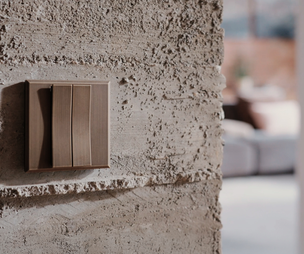 brass Sanipex switch plate on raw concrete wall