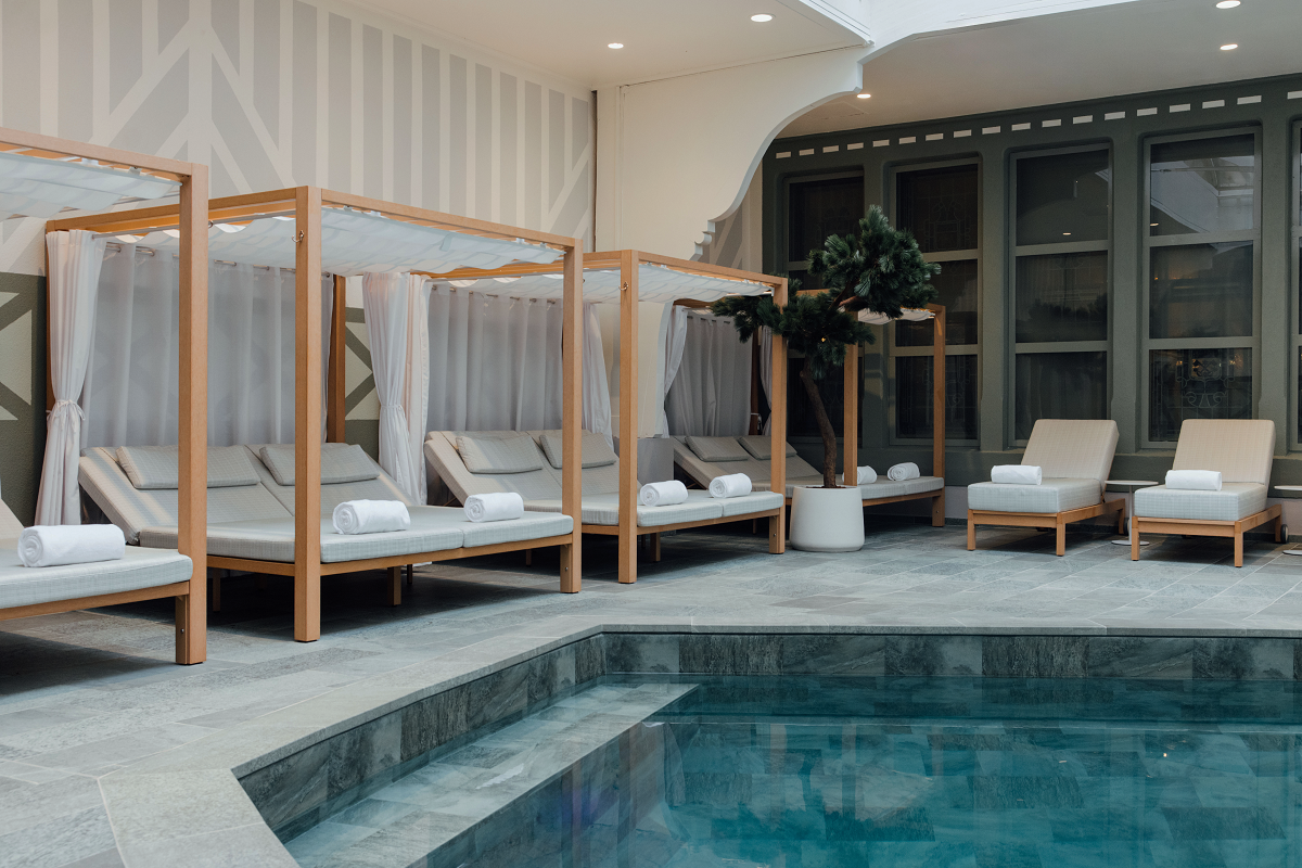 Indoor pool with sunlounger and cabana seats in Hotel Barrière Le Normandy