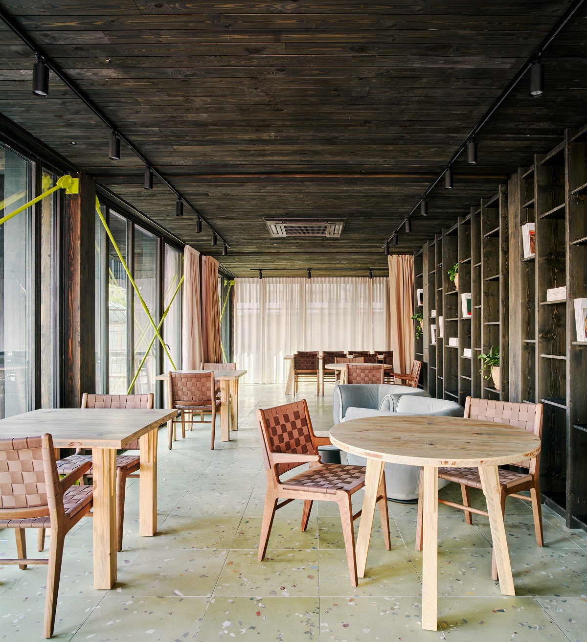 charred wooden ceiling , wood and leather furniture and stone floor in the co-working area of the hotel