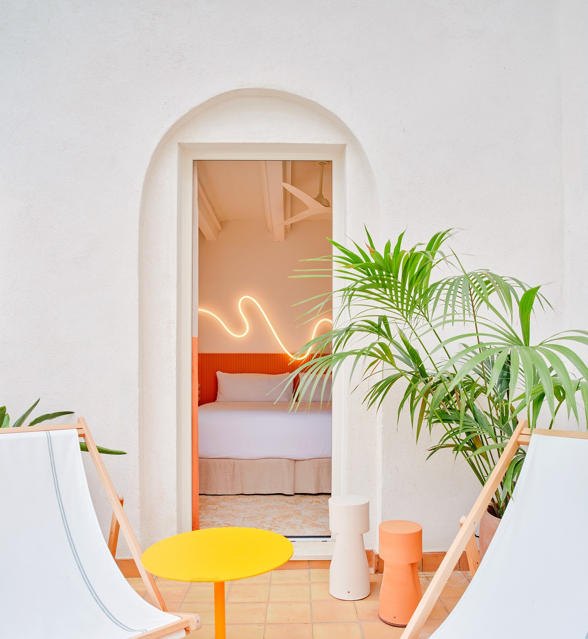white deckchairs with green palms in front of orange bedroom