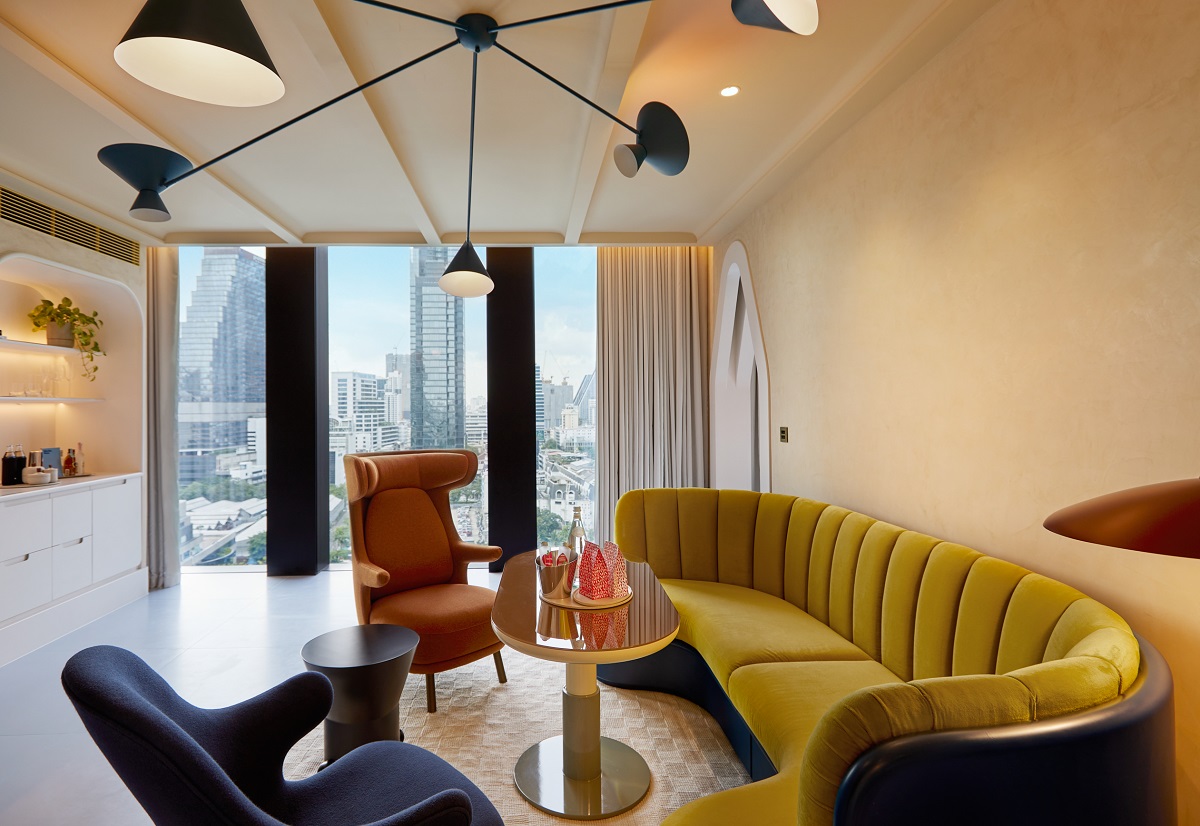 yellow curved couch in front of window with bangkok skyline