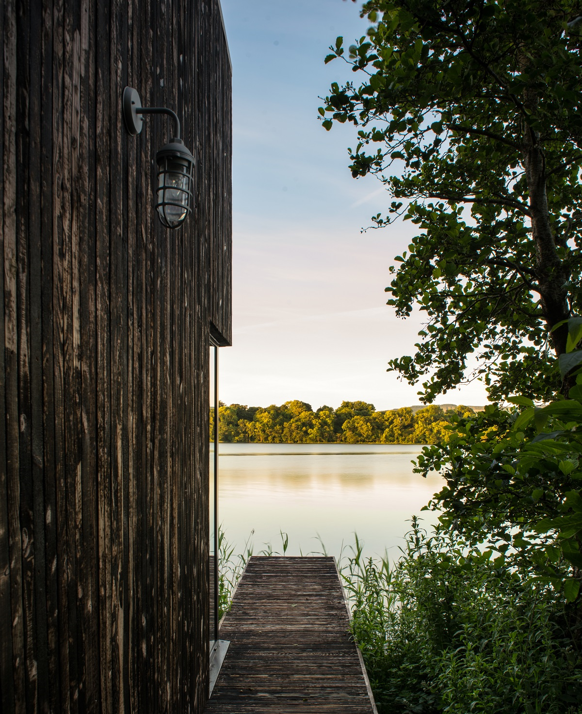 jetty leading to water alongside wooden cabin