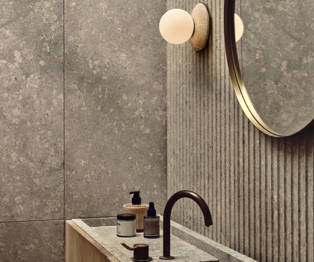 stone wall with focussed wall light next to bathroom mirror