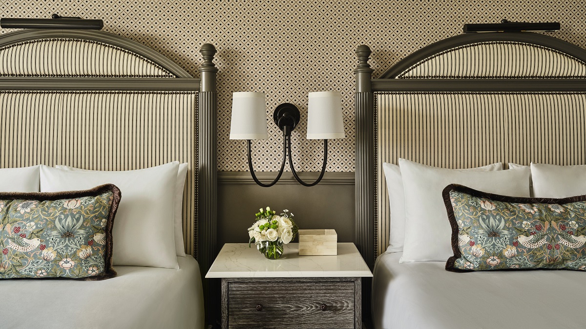 Biltmore guestroom detail with morris fabric cushion on bed, upholstered headboard and wallpaper