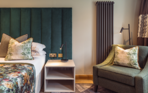 green upholstered headboard in hotel guestroom with Hamilton Litestat fittings