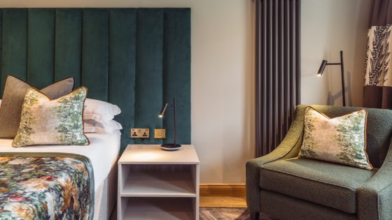 green upholstered headboard in hotel guestroom with Hamilton Litestat fittings