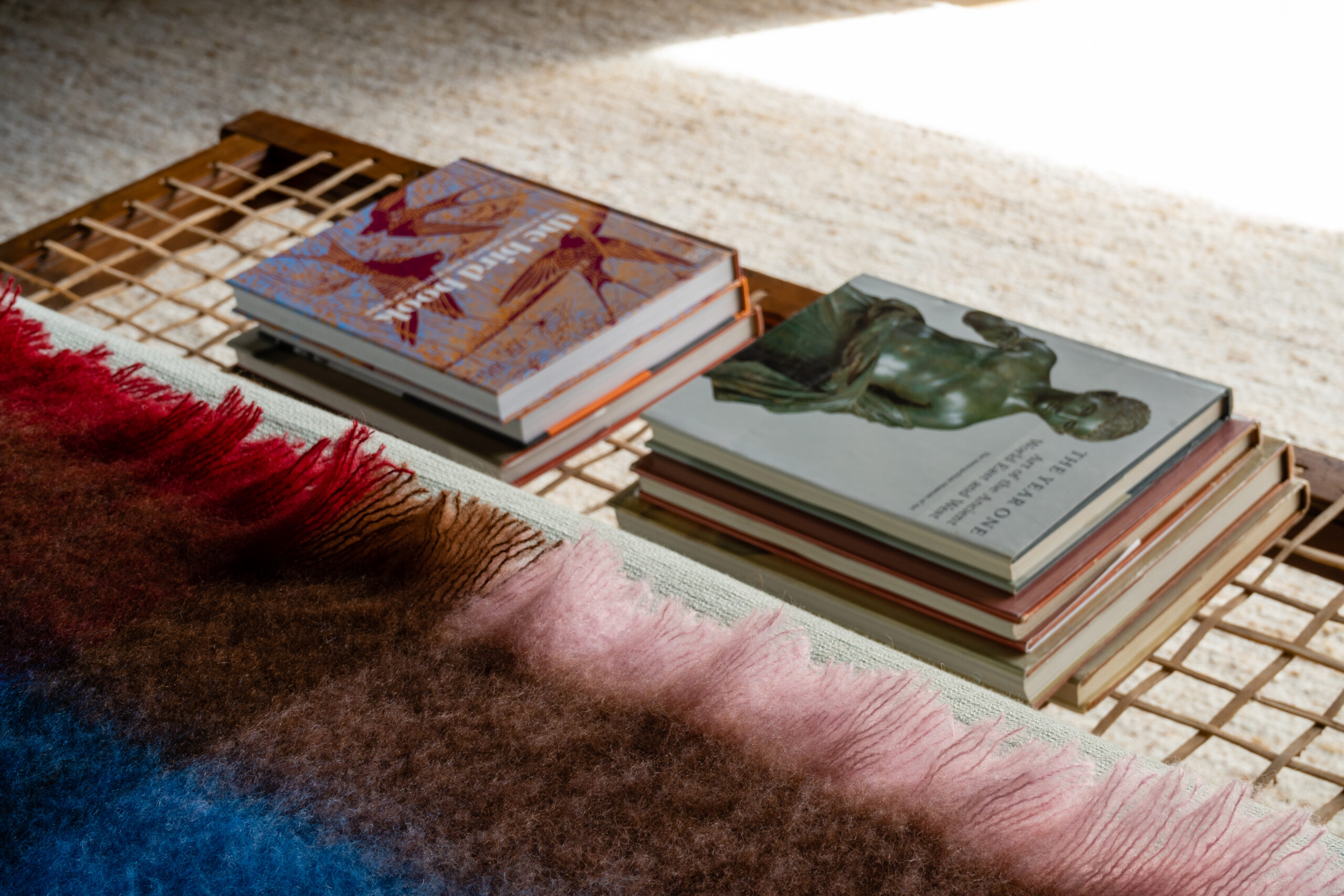 detail of woollen rug edge and stool with books