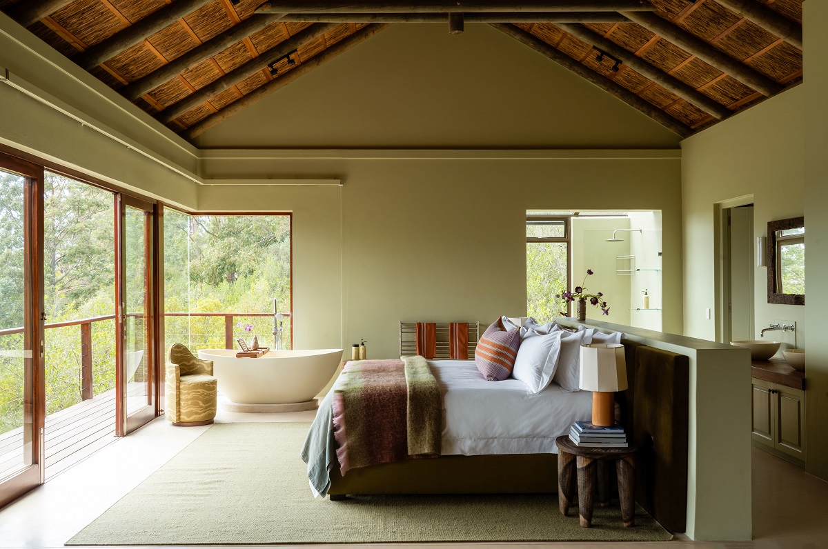 guestroom under thatched and beamed ceiling with views over natural flora on all sides