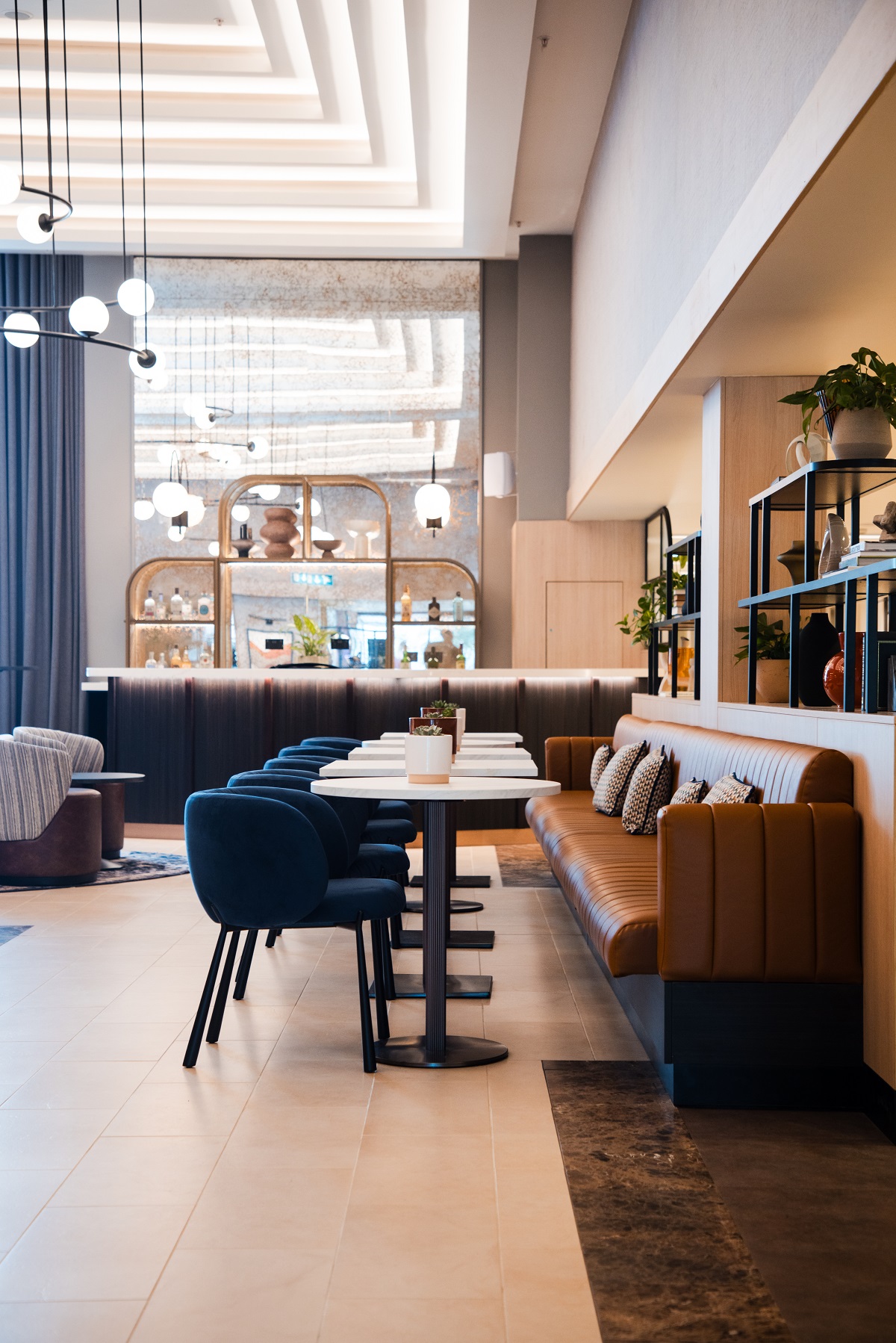 brown leather banquette, tables and blue chairs in Sheraton under Northern Lights lighting