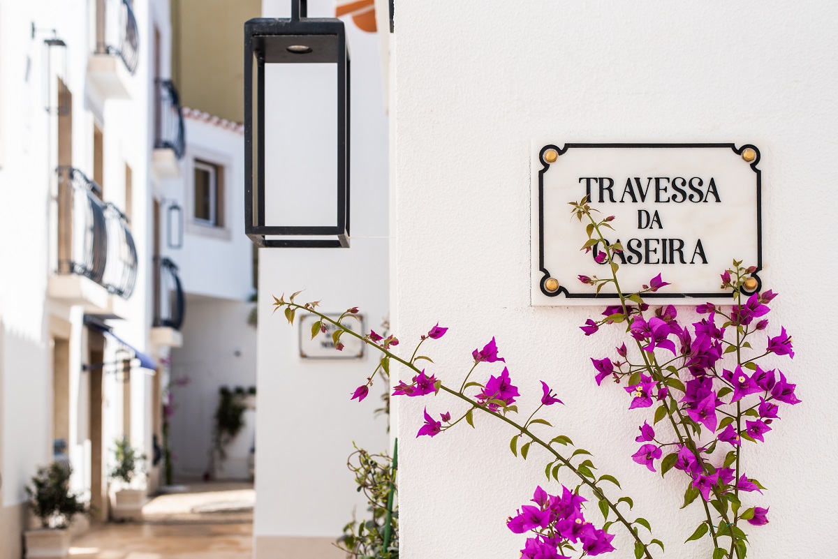 white walls , purple bougainvillea and hotel signage