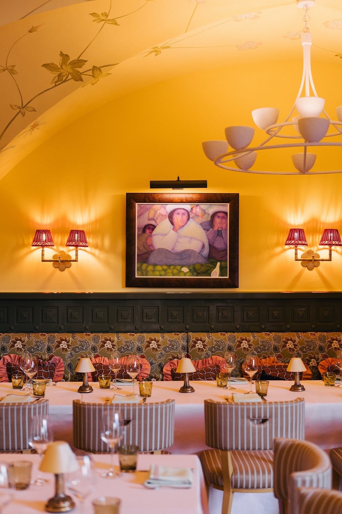 yellow vaulted ceiling in restaurant with statement chandelier and art