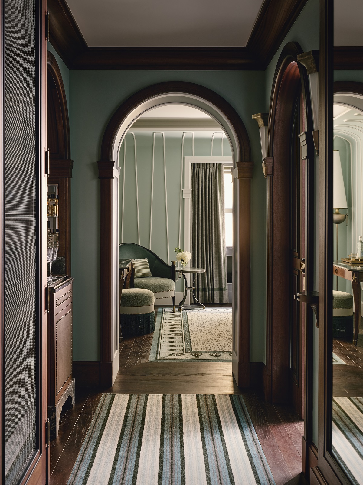 view down hallway with striped carpet into guestroom