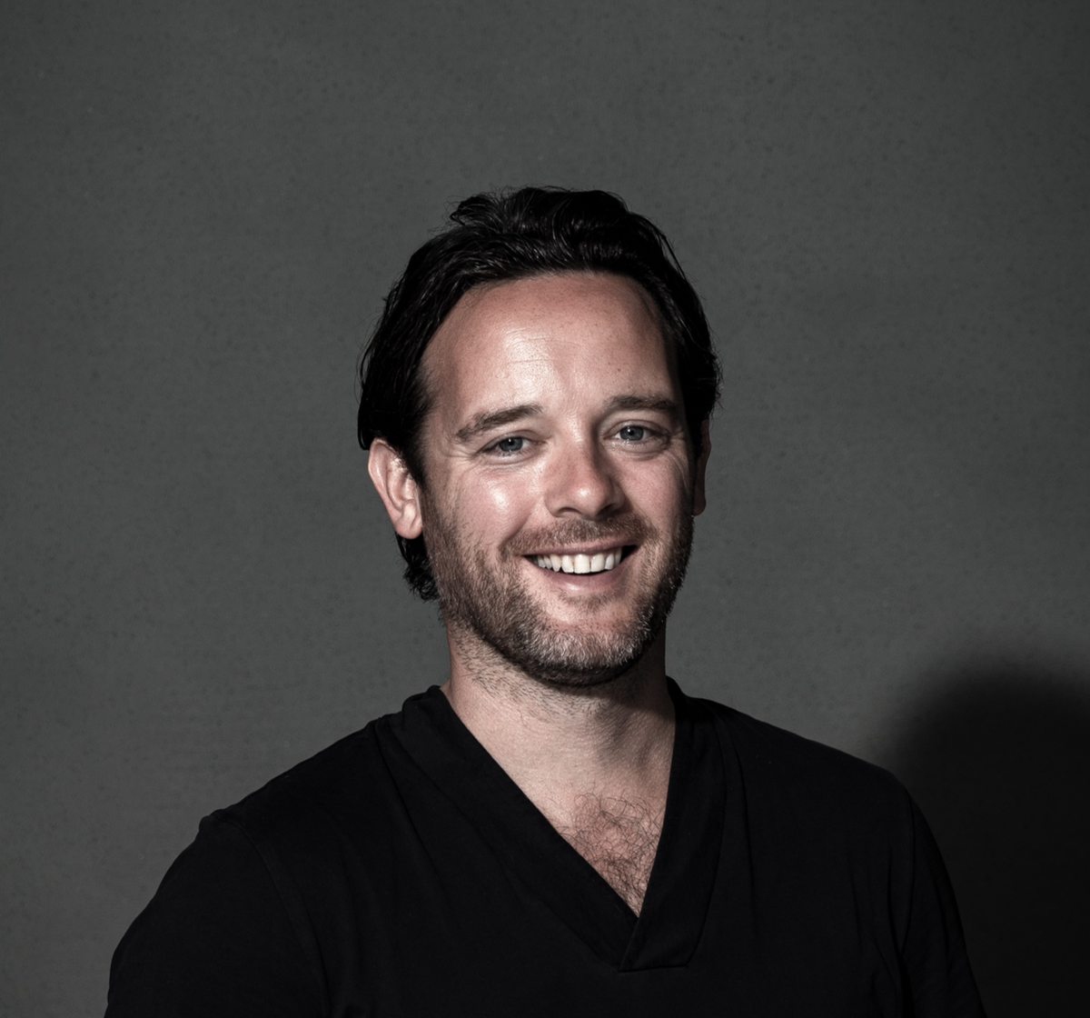 A headshot of Tom Chalmers, smiling to camera