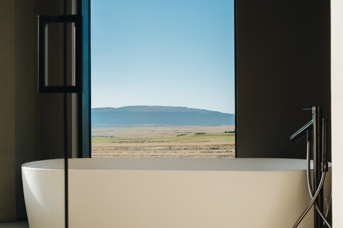 freestanding bath in front of floor to ceiling window with view over landscape