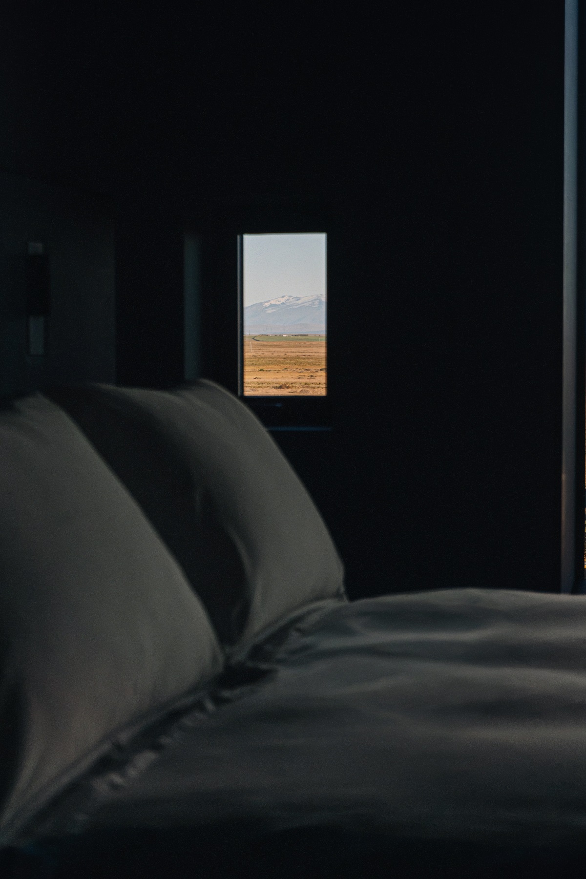 view of landscape from bed framed by small window