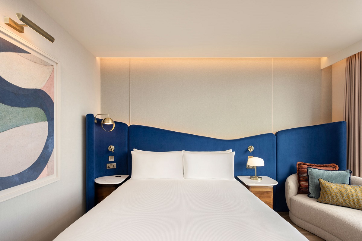 blue wrap around headboard and blue artwork in guestroom