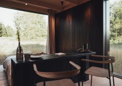 view from behind the bed and chairs in the Nokken cabin looking out to a grassy field