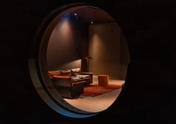 porthole window in Hotel Borsari looking on to minimalist furniture under a spotlight