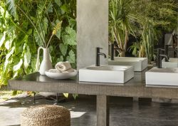 Double Ohtake basins in outdoor bathroom area, greenery surrounds