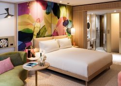 The BoTree guestroom with colourful abstract pattern behind bed