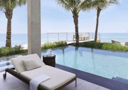 white sun lounger next to pool in front of palm trees and beach at Gran Meliá Nha Trang