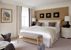 double bed in hotel guestroom alongside window with textiles and wallcovering in contemporary neutrals