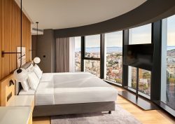 kingsize bed in guest room with cirved window overlooking split and wooden panelling behind the bed
