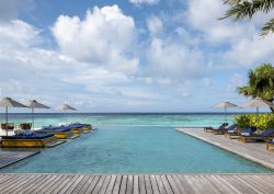 hotel infinity pool surrounded by wooden deck extending out to sea on island in the Maldives
