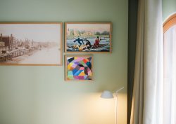 sage green wall in a hotel guestroom with a curated gallery art wall