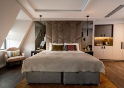 grey bed with white linen on wood floor in aparthotel suite Adina The Hobson