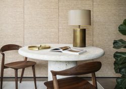 wooden chairs around a stone coloured organic shaped table in front of natural raffia textured wallcovering from Arte