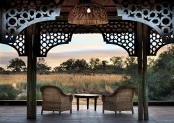 two wicker chairs framed by building looking out over african savannah view