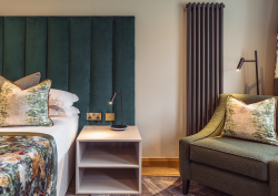 green upholstered headboard in hotel guestroom with Hamilton Litestat fittings