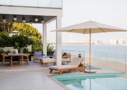 white deck on the beach with wood and white umbrella and furniture