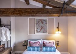 Bedroom inside luxury apartment in Venice with wooden beams over ceiling