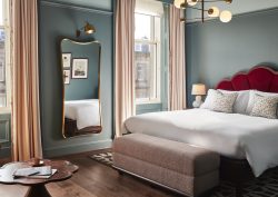 blue guestroom walls, red headboard and period sash windows in Hoxton Edinburgh