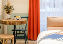 natural raw edge wood table in hotel room2 belfast guestroom decorated in olive green and orange