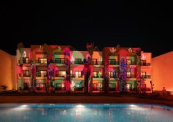 night lights across pool and cactus mural at Kaktus Hotel & Co-Working Hub, SomaBay