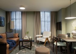 brown leather sofa with blue throw and grey and taupe walls and fabrics in Cove Kensington Apartment