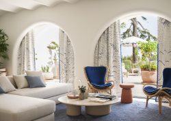 table and sofa in front of arched doors leading onto terrace and pool at Jumeirah Capri Palace