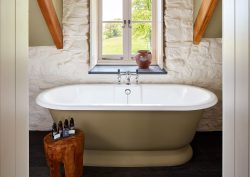 roll top bath in front of window in beamed country bathroom