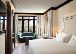 guestroom in hotel montera madrid with white linen on double bed and blue couch in window overlooking madrid