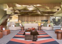 kimpton algarve lobby with orange and brown patterned carpet below gold sculptural ceiling installation