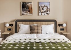 wooden bed with green and white bedlinen in Faern Arosa Altein guestroom