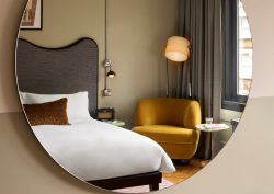 Organic circle mirror showing reflection of bed at Hoxton Shoreditch