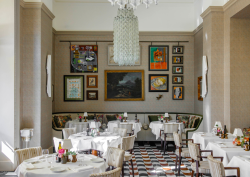 Restaurant space at Hotel Savoy, with brightly coloured gallery wall and large glass chandelier