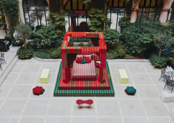 Raised on a platform and framed by bold red and green pillars, the ‘Day Bed’ structure feels at once playful and monumental. A fusion of sharp lines and organic shapes, the installation is industrial yet sumptuous. Low stools and benches in bright, Crayola hues are scattered across the tiled courtyard, inviting visitors to pause and take in the scene. With its bold palette of Plaza red and garden green, Uchronia has transformed the Hôtel Plaza Athénée courtyard space into a contemporary cubist exhibition, where – like a strange dream – a geometric bed awaits sleep outside, encased within the white walls of historic Paris.